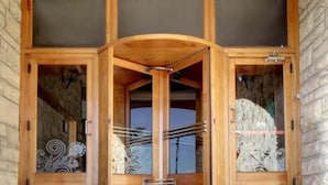 Een houten kast met glazen deuren, versierd met ingewikkeld metaalwerk op het glas.