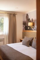 A hotel room with a bed, a nightstand, a lamp, and a window with curtains.