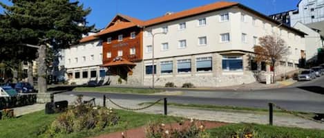 Un hotel con fachada de piedra, múltiples ventanas y techo rojo.