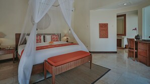 A bedroom with a four-poster bed, a wooden bench, a desk, and a chair. - Parigata Villas Resort (Denpasar)