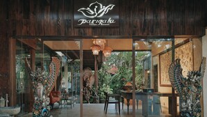 The entrance of Parigata Villas Resort with a wooden facade, glass doors, and decorative statues. - Parigata Villas Resort (Denpasar)