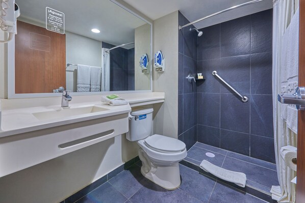 Un baño moderno con lavamanos, inodoro y zona de ducha blancos.