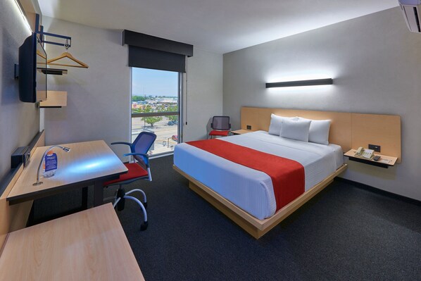 Une chambre d’hôtel comprenant un lit, un bureau avec une chaise, une petite table, un téléphone et une vue sur l’extérieur.