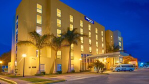 A hotel with a modern facade, multiple floors, and a well-lit entrance.