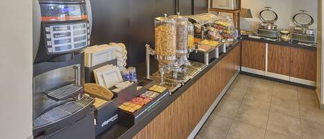 A breakfast bar with a coffee machine, cereal dispensers, and a variety of food options.