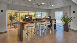 A reception area with a wooden counter, several white chairs, and a potted plant.
