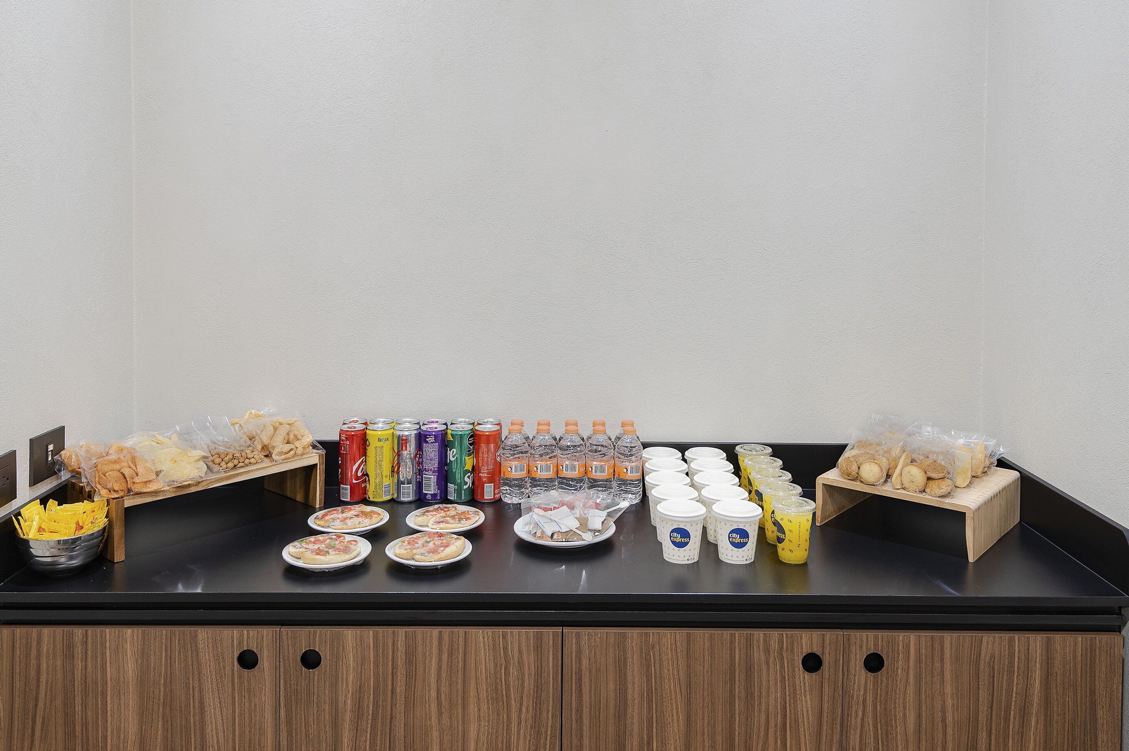 A buffet table with various food items, drinks, and containers.