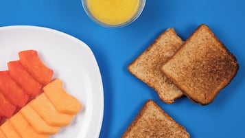A plate with slices of toast and carrot sticks on a blue background.