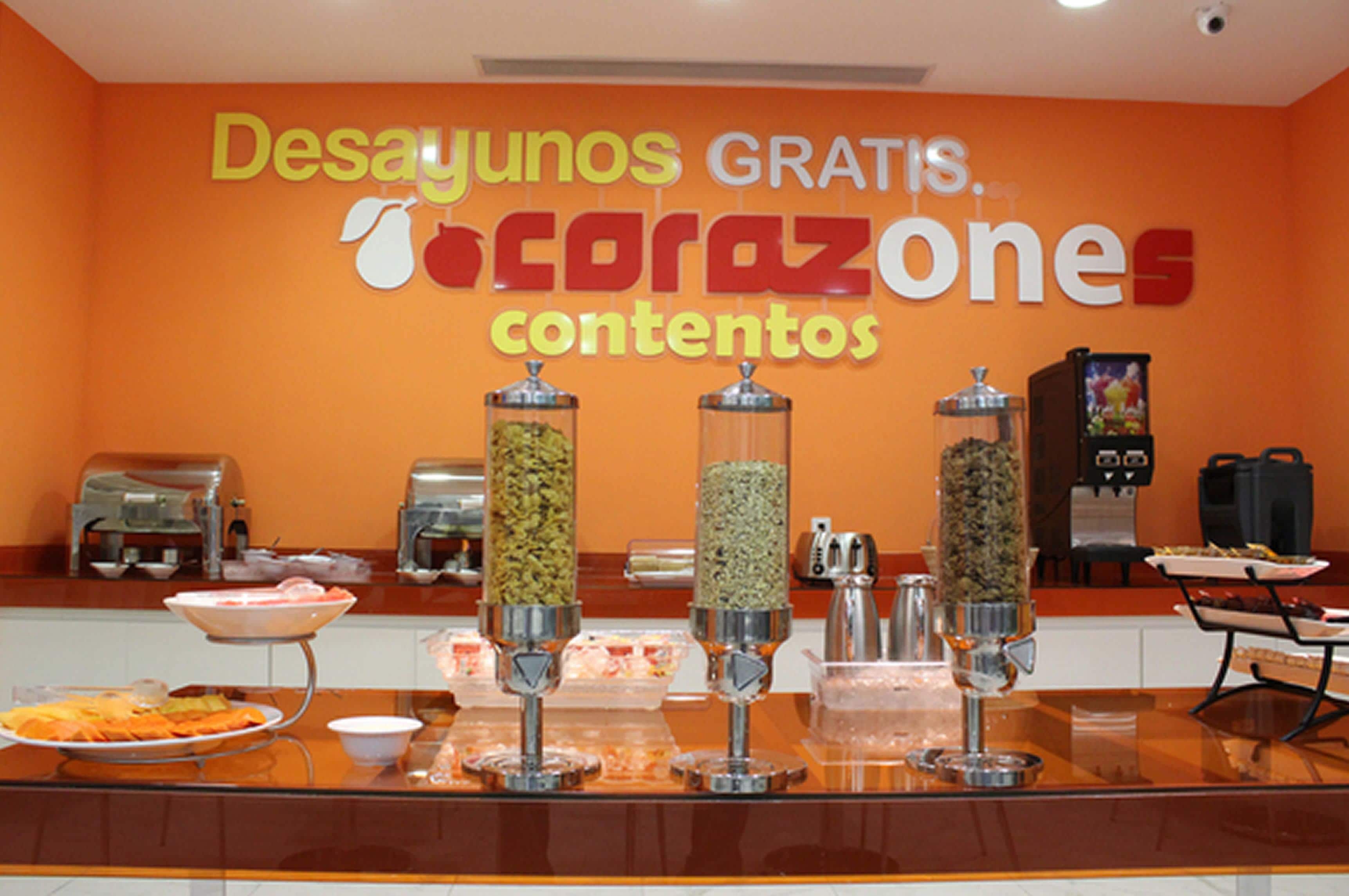 A buffet area with a sign reading "Desayunos Gratis. Tocrazones contenidos" and various food dispensers.
