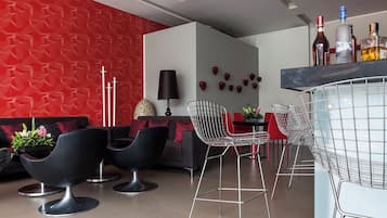 A modern interior with a red textured wall, black and red seating, a bar area, and a decorative wall with heart shapes.