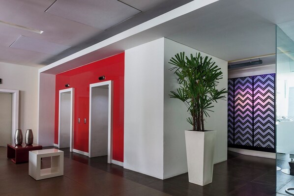 Un vestíbulo moderno con una paleta de colores rojo y blanco, una planta grande en maceta y una pared con diseño en zigzag.