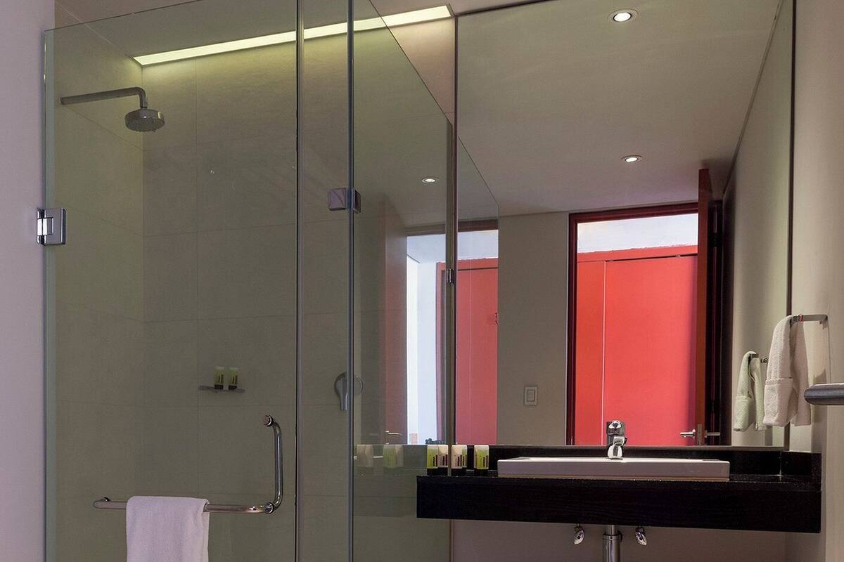 A modern bathroom with a glass-enclosed shower, a large mirror, and a black countertop with a sink.