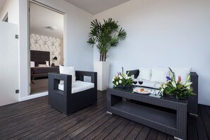 A modern outdoor seating area with a wicker sofa, a small table with a drink, and a potted plant. - Gamma Morelia Beló (Morelia)
