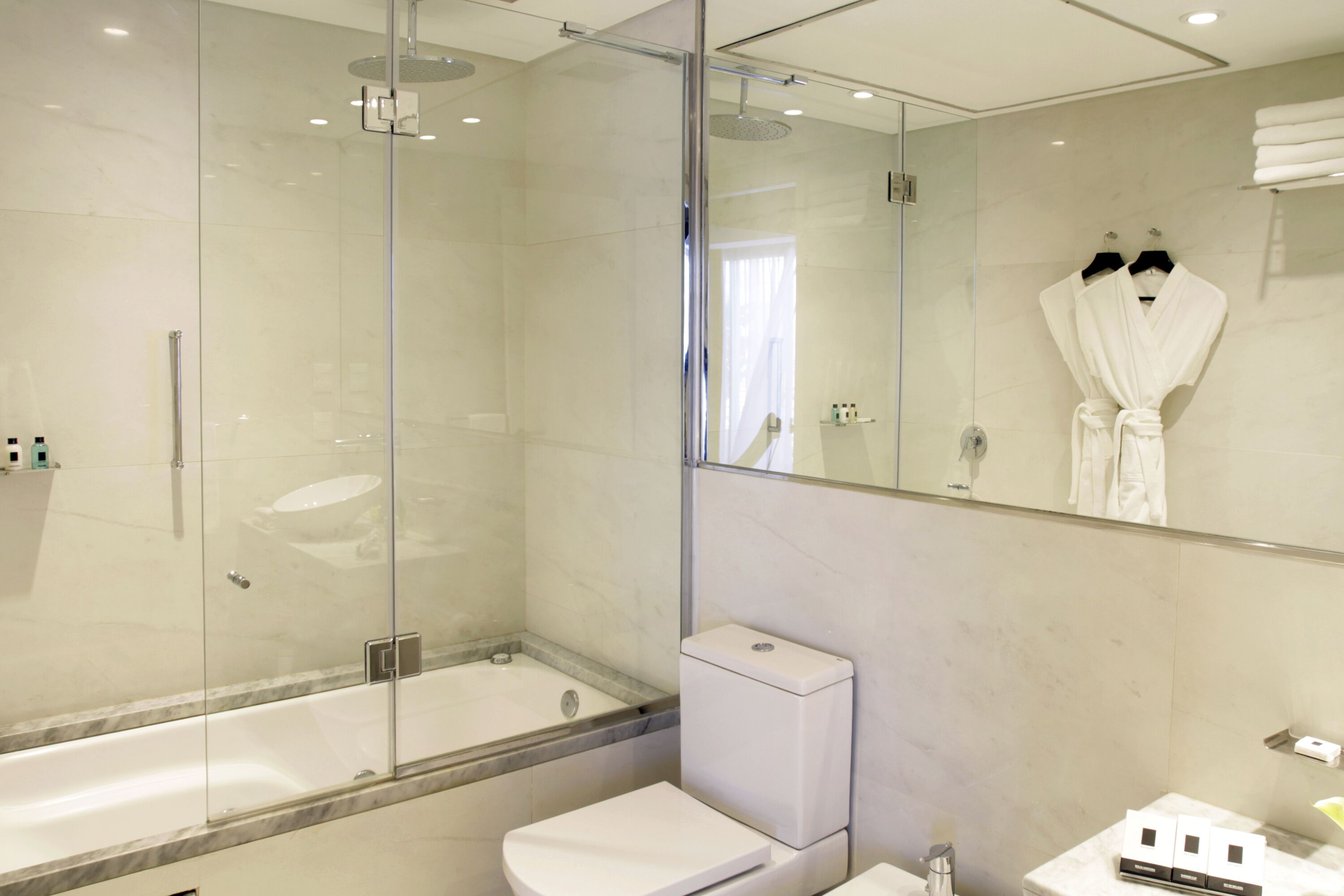 Une salle de bain moderne avec une douche à parois de verre, des toilettes blanches et un lavabo.