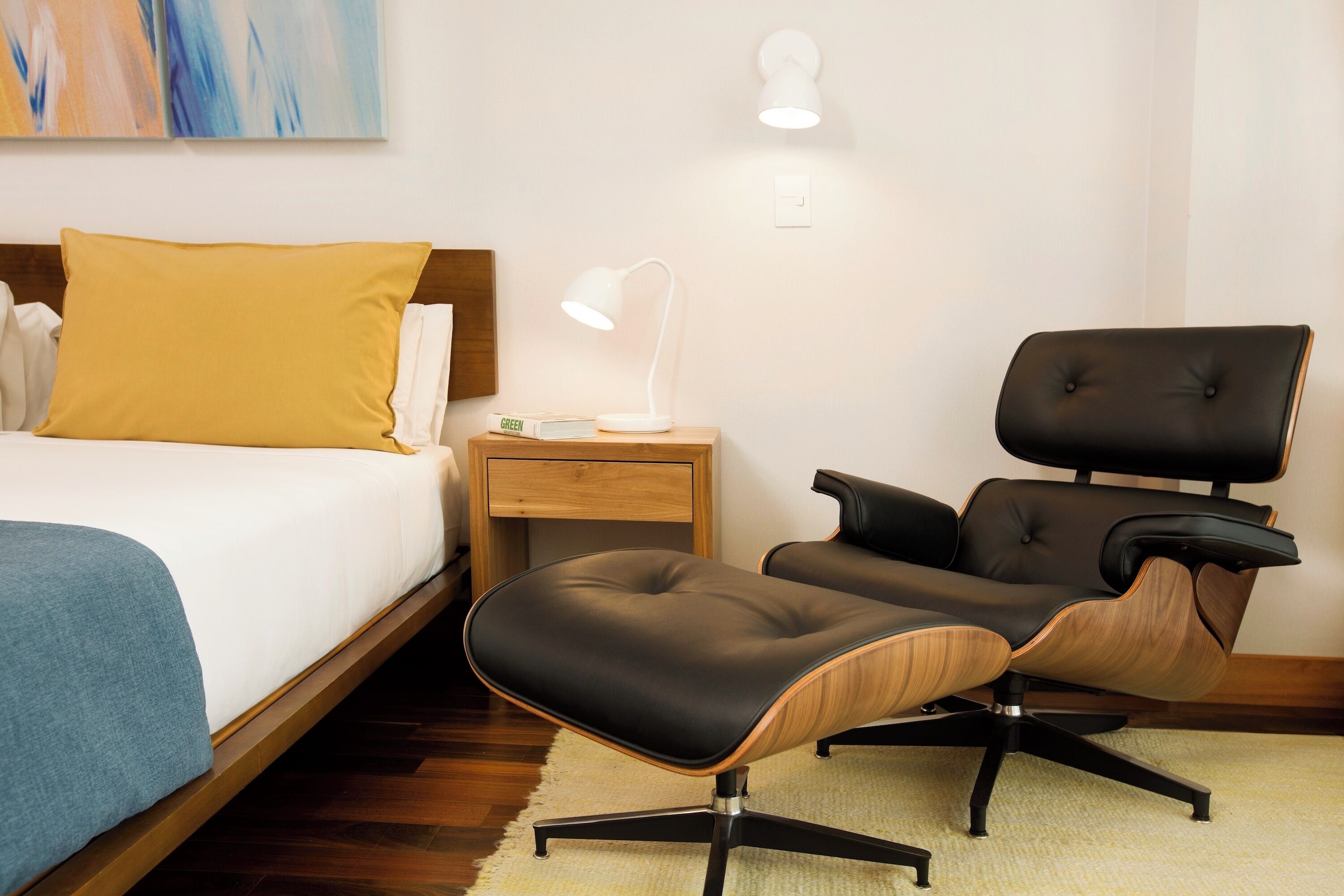 A hotel room with a bed, a desk, a chair, and a lamp.
