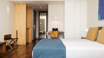 Una camera d'albergo con un letto grande, una scrivania con una sedia, un armadio e un quadro appeso al muro.