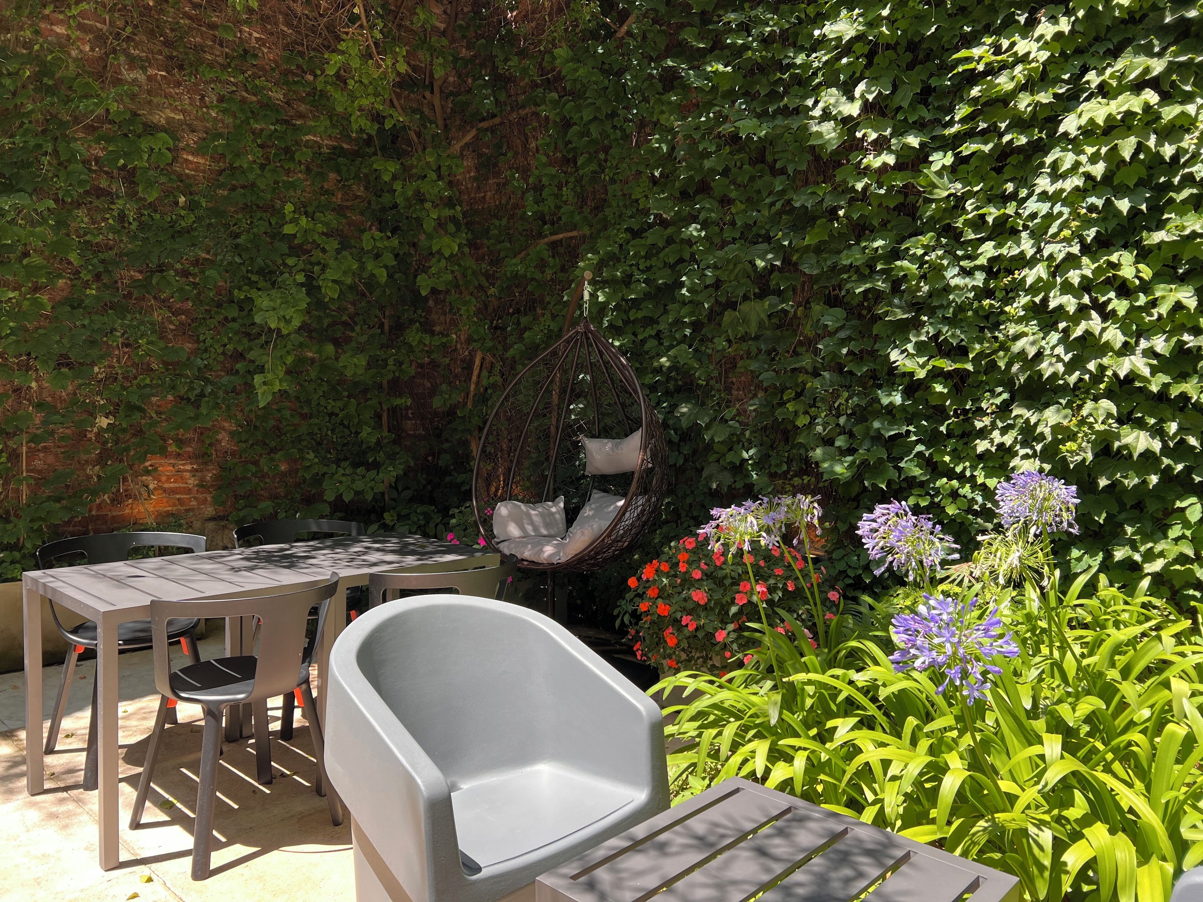 An outdoor seating area with a table, chairs, and a hanging chair.