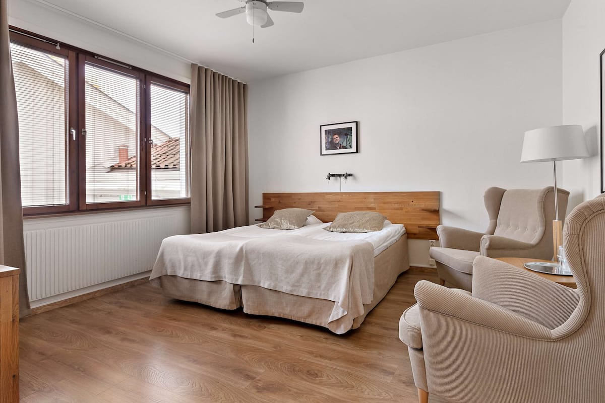 Een slaapkamer met een bed, een stoel, een lamp en een raam met jaloezieën.