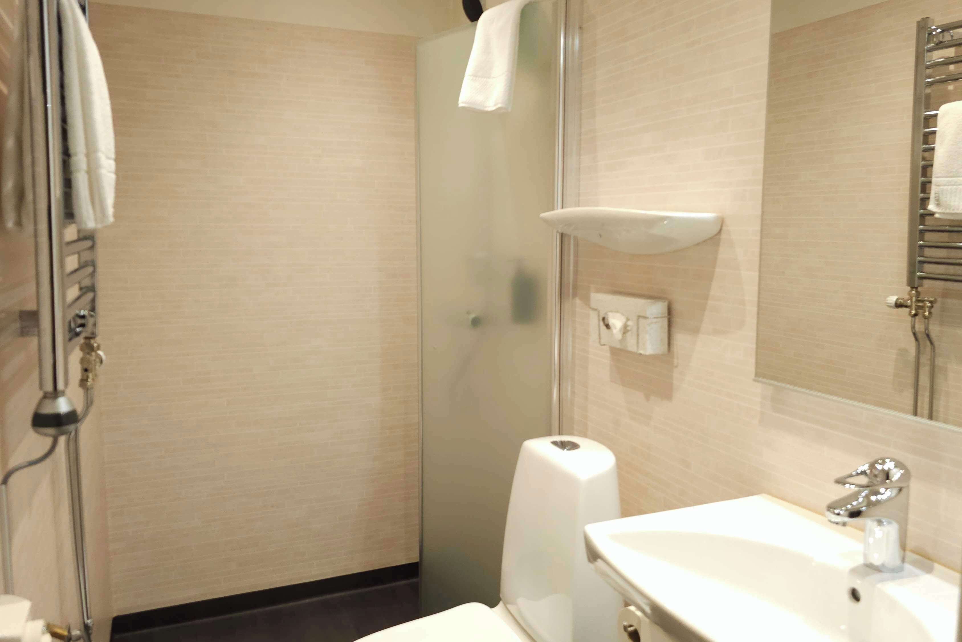 A bathroom with a toilet, sink, and glass shower enclosure.
