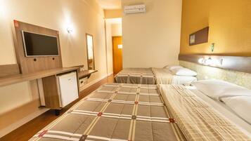 A hotel room with two beds, a TV, a mini-fridge, and a mirror.