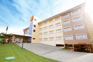 Un hotel de varios pisos con techo plano, zona de estacionamiento y un cartel que indica un límite de altura de 2 metros.