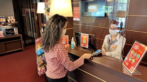 Un mostrador de recepción de hotel con un quiosco digital, un espejo y carteles informativos.