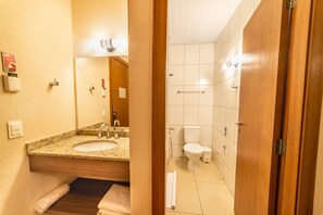 Un baño con lavamanos de encimera de granito, un espejo, un inodoro y una puerta de madera.