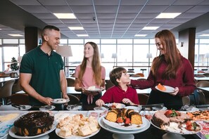 Un groupe de personnes se trouve près d’un buffet proposant divers desserts et un grand gâteau.