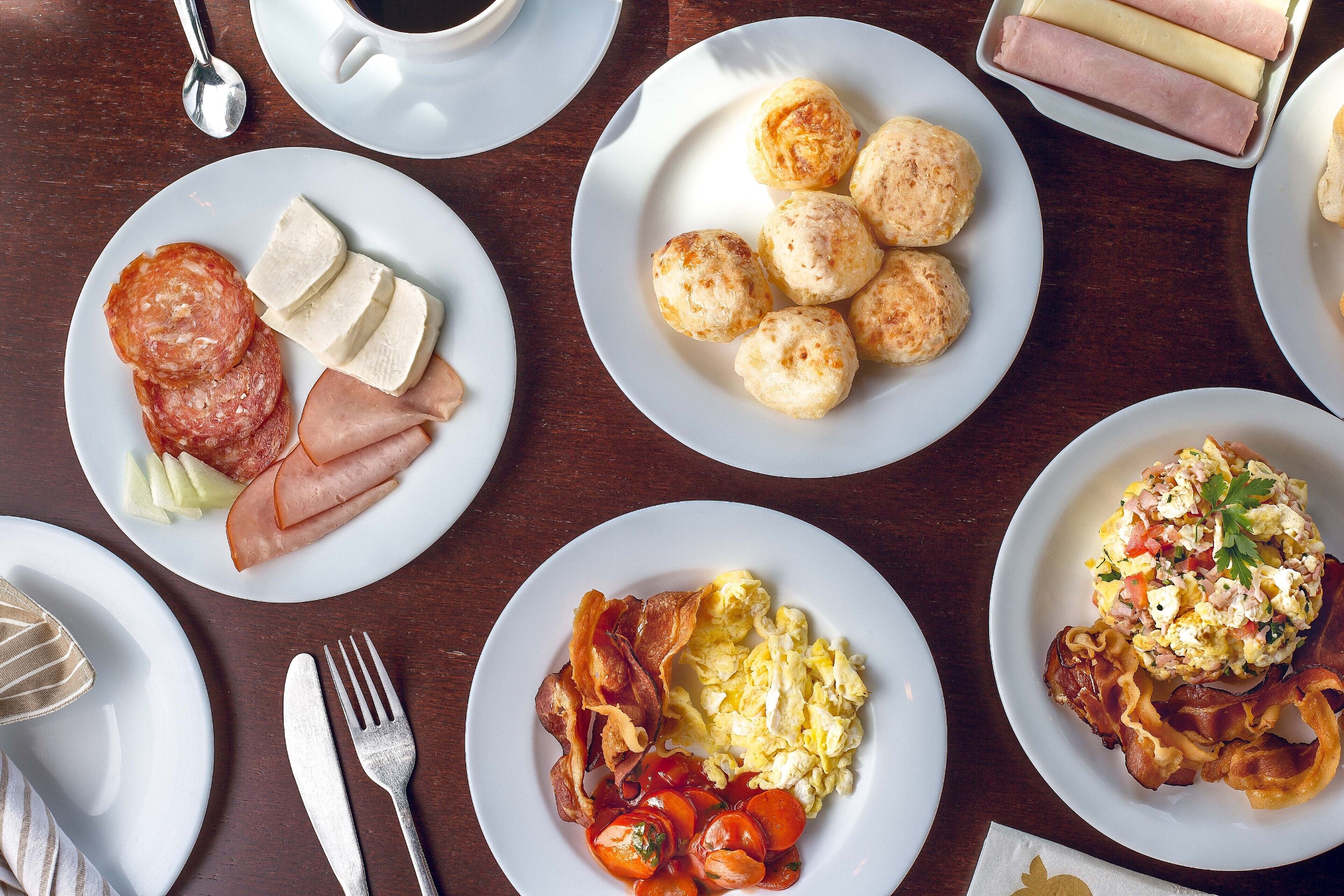 A breakfast spread with various dishes including eggs, bacon, sausages, and pastries.