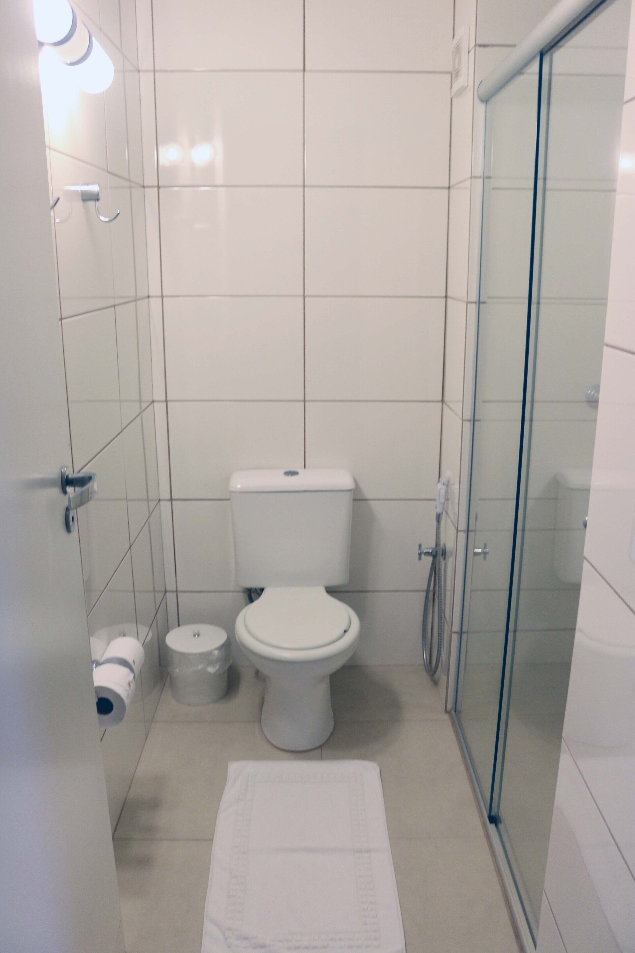 A bathroom with a toilet, a glass shower enclosure, and a white sink.