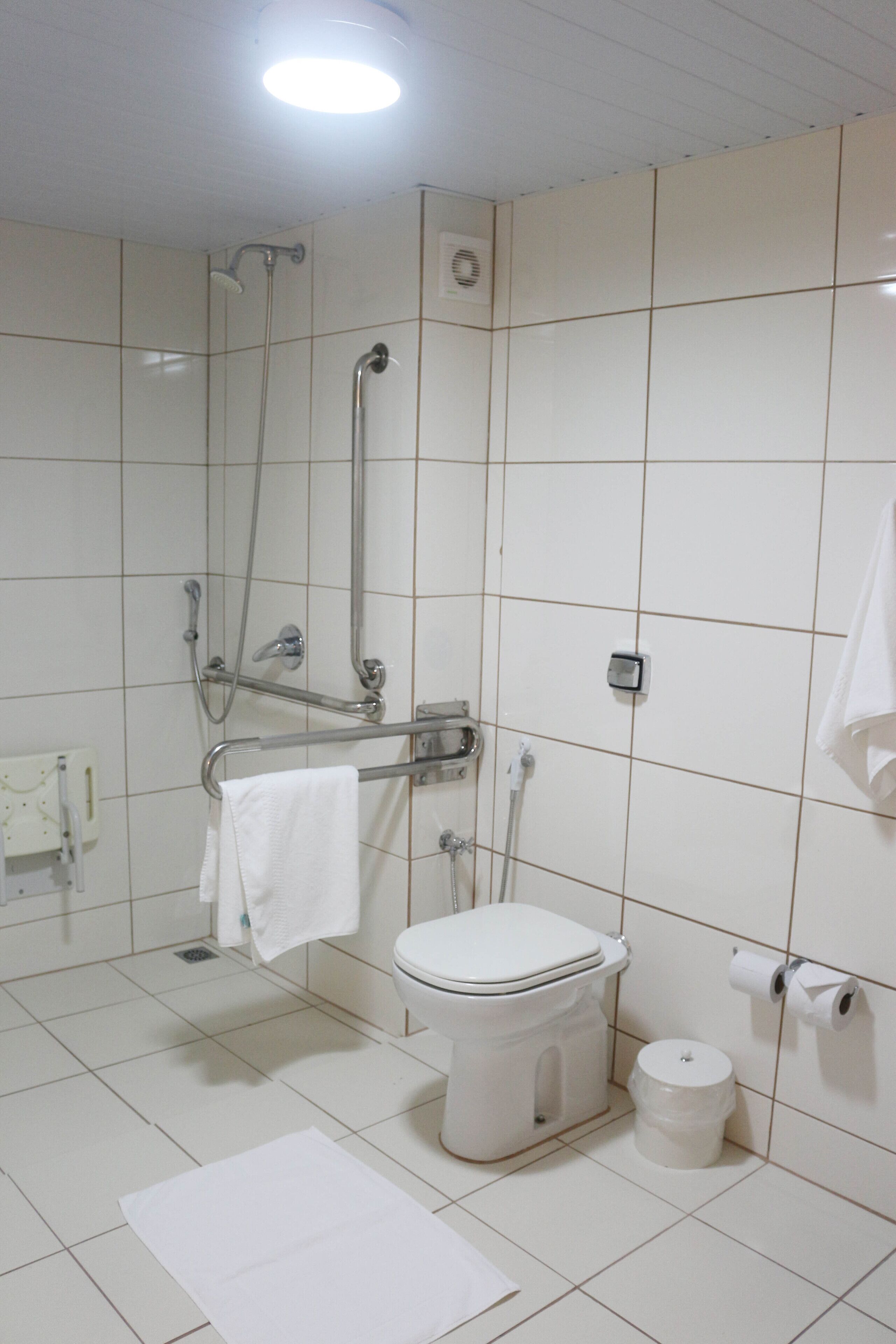 A bathroom with a toilet, a shower, and a hand dryer.