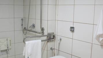 A bathroom with a toilet, a shower, and a hand dryer.