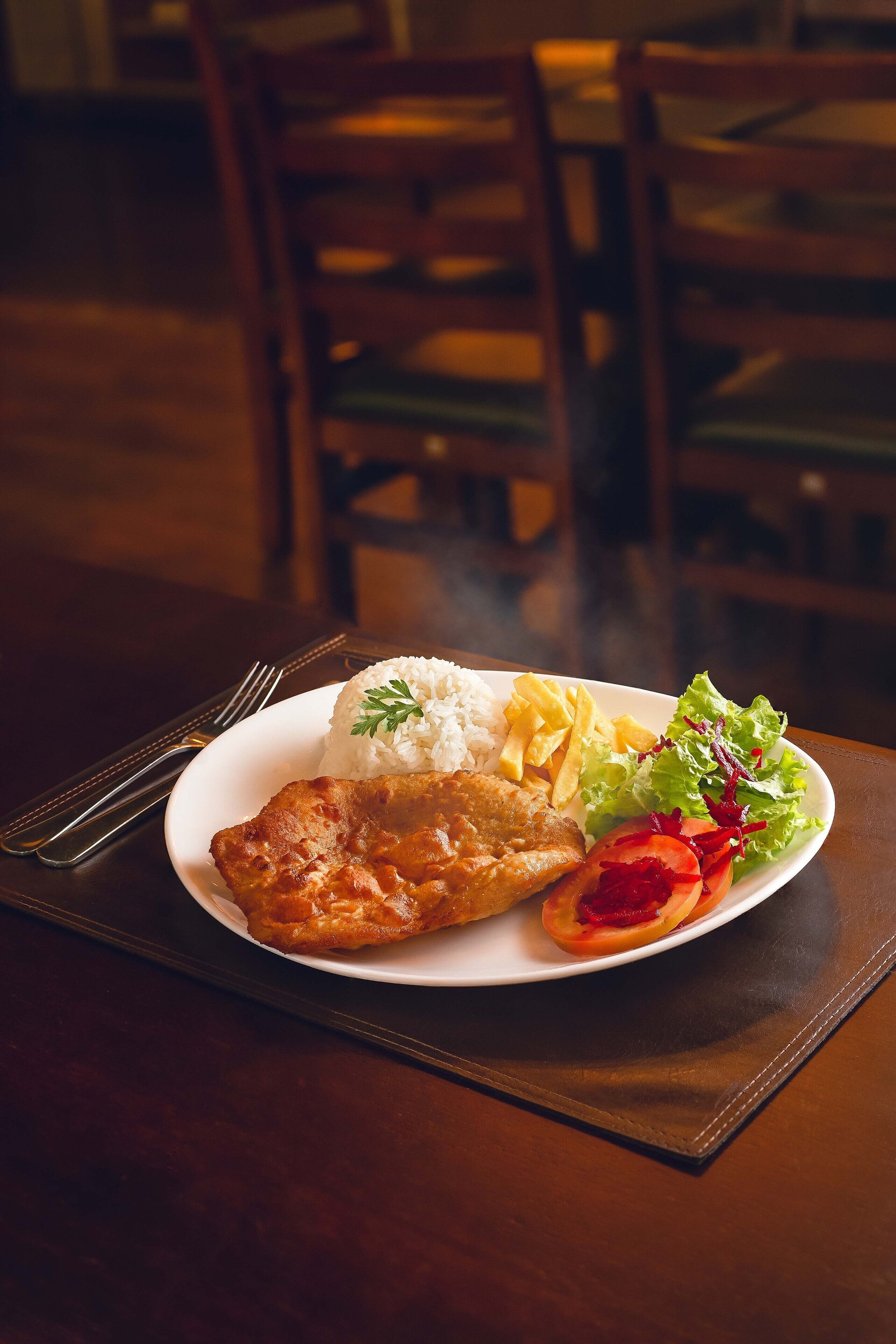 Un plato de comida con arroz, pollo frito, papas fritas y una ensalada.