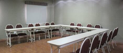 A conference room with a long table and chairs, a projector screen, and a whiteboard.