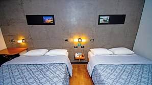 A hotel room with two beds, a wooden nightstand, a telephone, and two wall-mounted light fixtures. - H+ Hotel (Dourados)