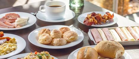 A breakfast buffet with various dishes including eggs, sausages, and pastries.