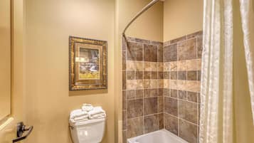 A bathroom with a toilet, a framed picture on the wall, and a shower area with a curtain.