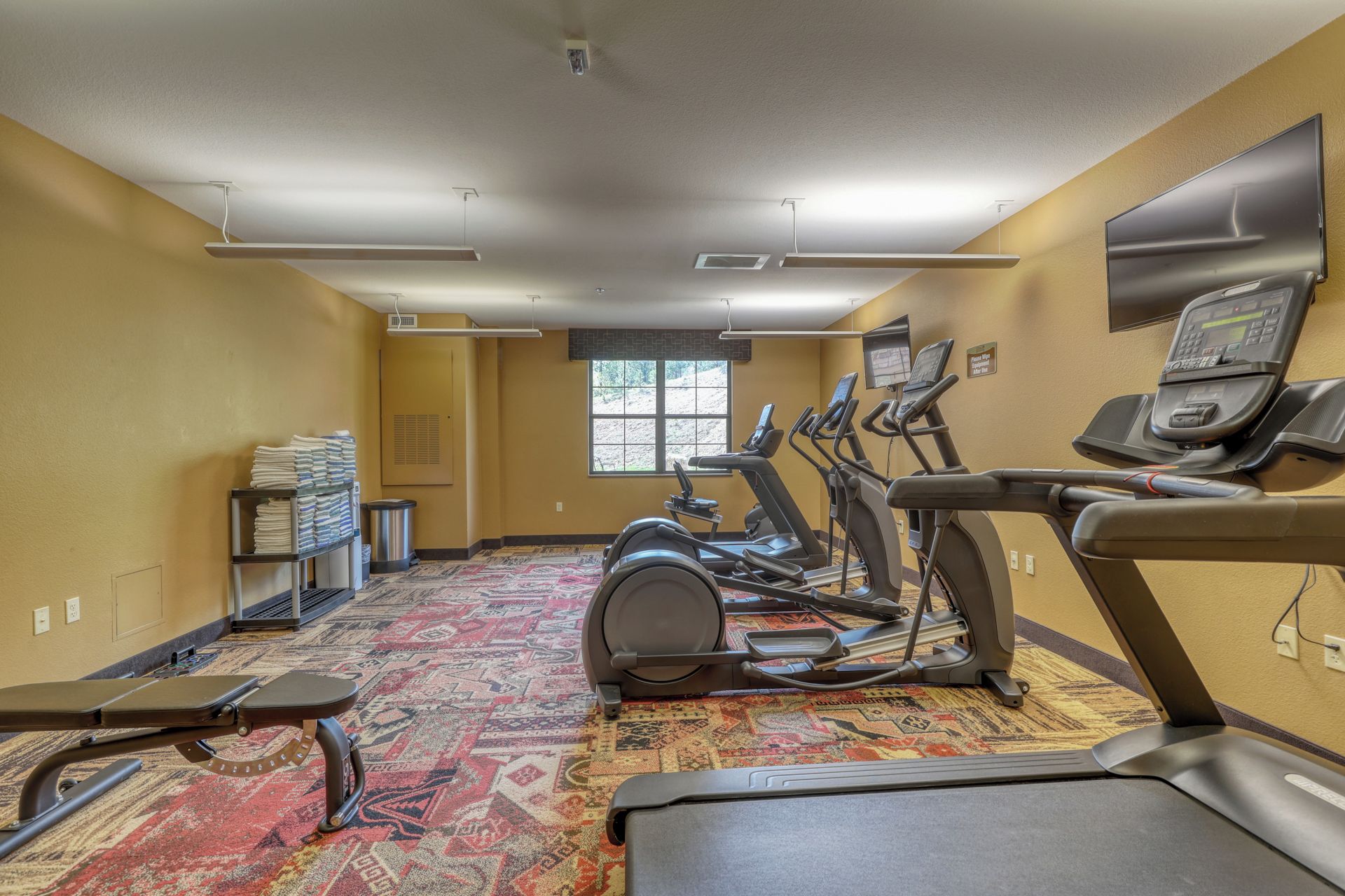 A gym with multiple treadmills, a stationary bike, and a wall-mounted television.