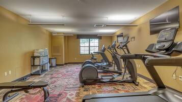 A gym with multiple treadmills, a stationary bike, and a wall-mounted television.