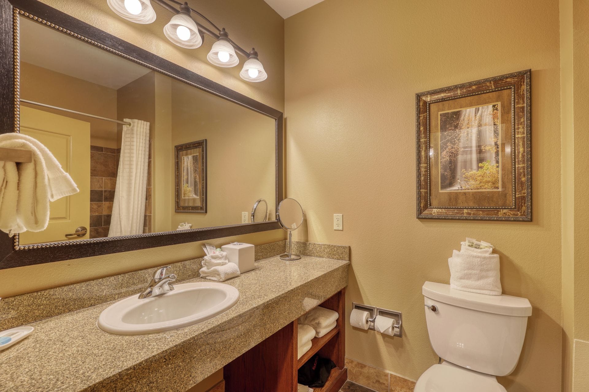 A bathroom with a sink, mirror, toilet, and towel rack.