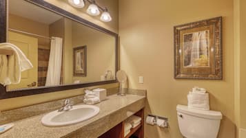A bathroom with a sink, mirror, toilet, and towel rack.