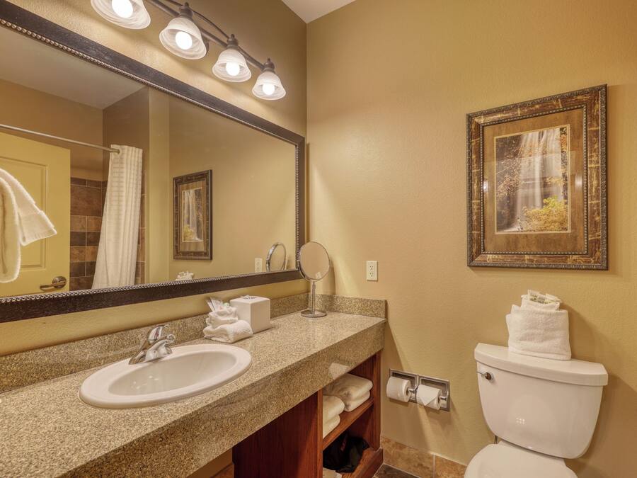 A bathroom with a sink, mirror, toilet, and towel rack.