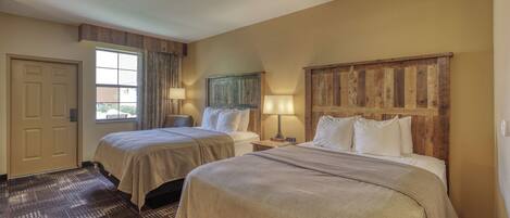 A hotel room with two beds, a wooden headboard, a window with curtains, and a patterned carpet.