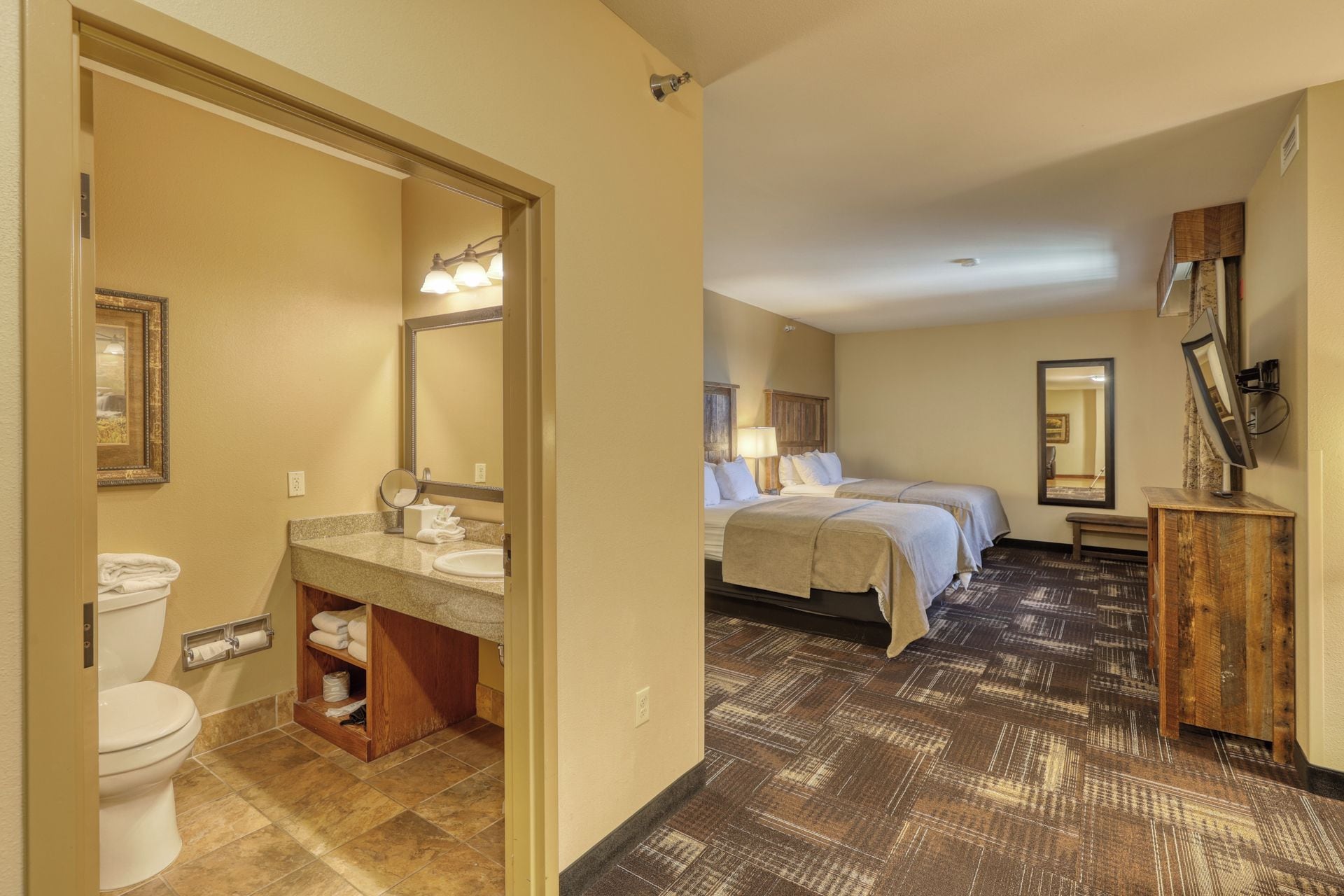 Une chambre d’hôtel avec une salle de bain, un lit avec deux oreillers, une table de chevet et un miroir.