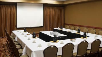 A conference room with a long table, chairs, a projector screen, and a whiteboard.