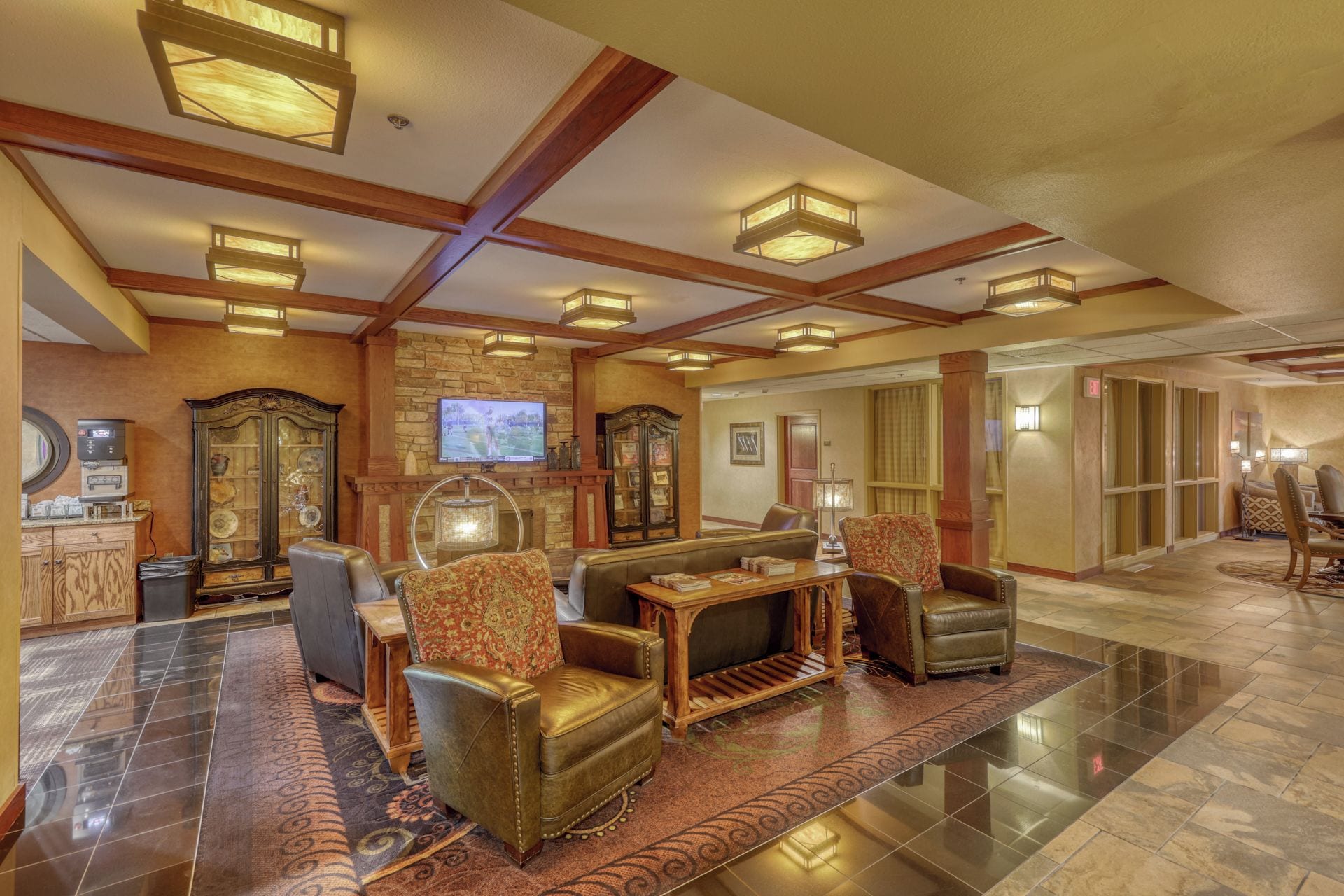 A spacious lobby with a fireplace, leather seating, and a television.