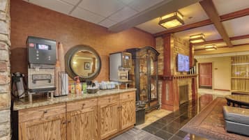 A hotel lobby with a coffee station, a fireplace, and a television mounted on the wall.