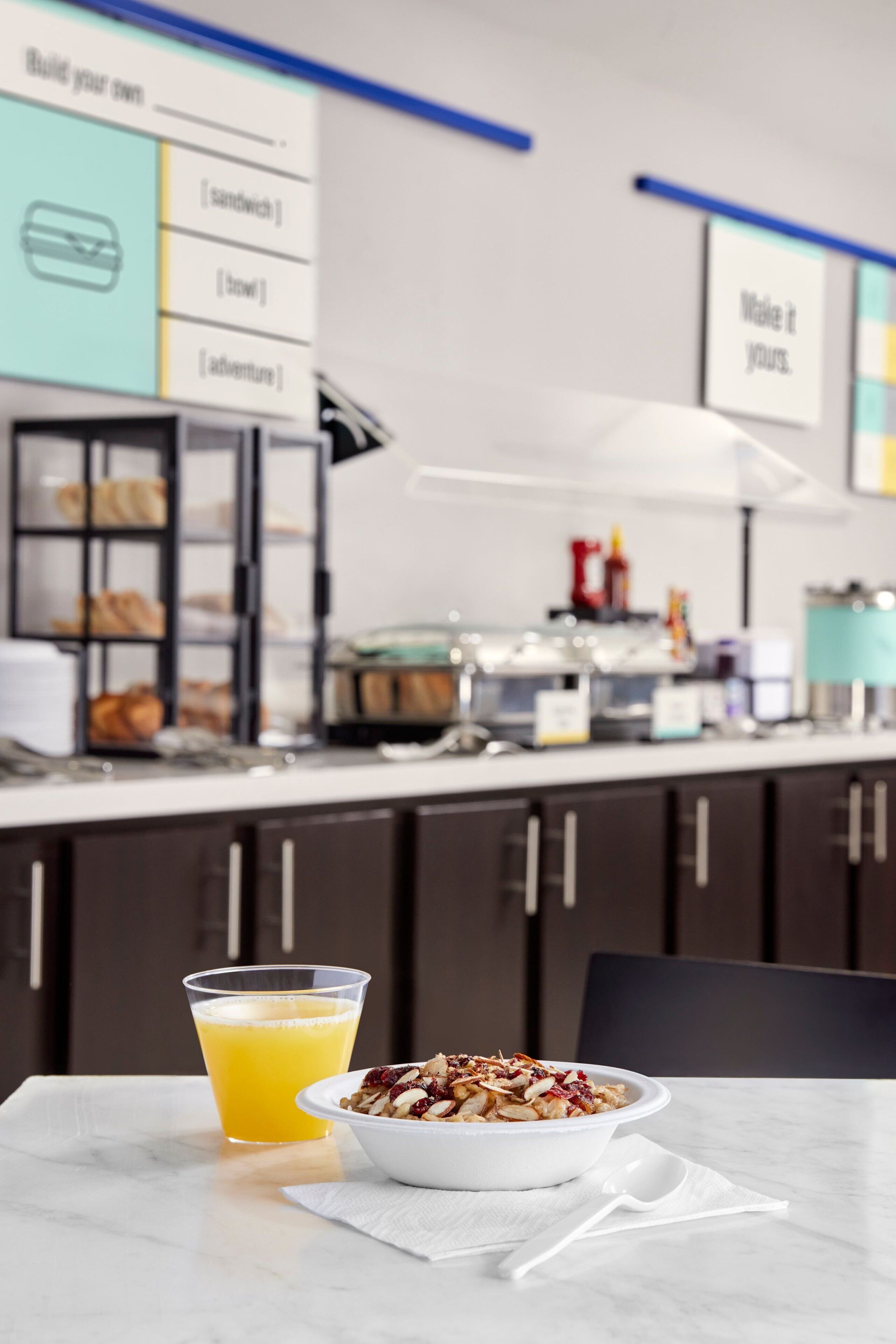 Desayuno con un tazón de cereal y un vaso de jugo de naranja sobre una mesa.