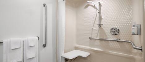 A bathroom with a walk-in shower, grab bars, a towel rack, and a handheld showerhead.