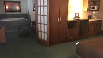 Une chambre d’hôtel comprenant un lit, un bureau, une chaise, une petite table, un placard, un four à micro-ondes, un évier et une baignoire.
